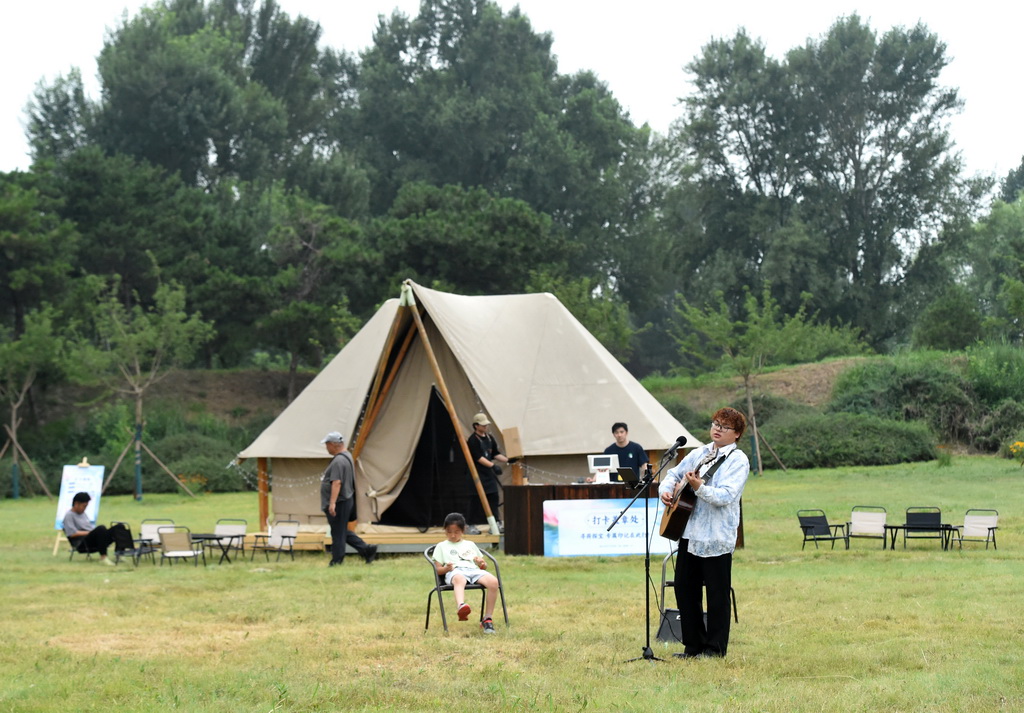 6月28日,一名歌手在圆明园“风荷朝露帐篷咖啡”处弹唱。