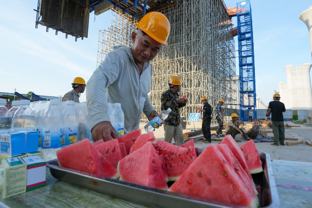 7月3日，中铁上海工程局的工人在宁淮城际铁路（南京至淮安）5标项目跨203县道连续梁施工现场吃西瓜、休息。
