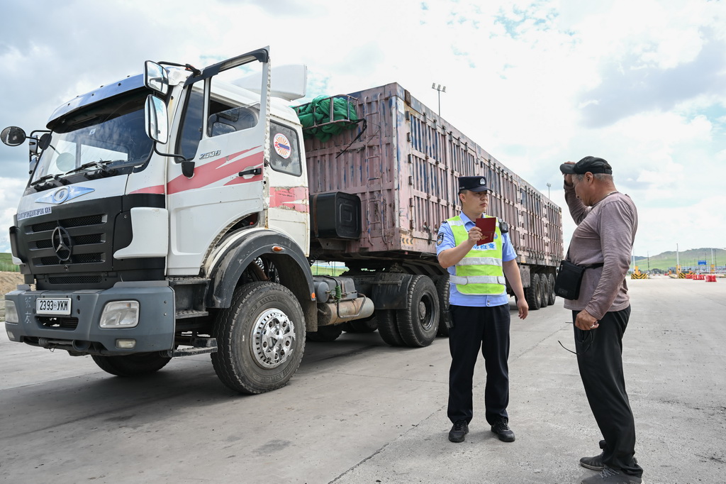 7月10日，在珠恩嘎達布其口岸，珠恩嘎達布其出入境邊防檢查站移民管理警察（左）查驗貨車司機証件。