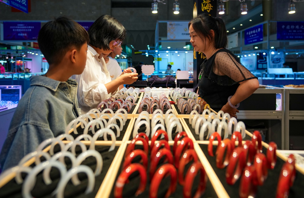 7月10日,消费者(左二)在昆明石博会上挑选玉石。