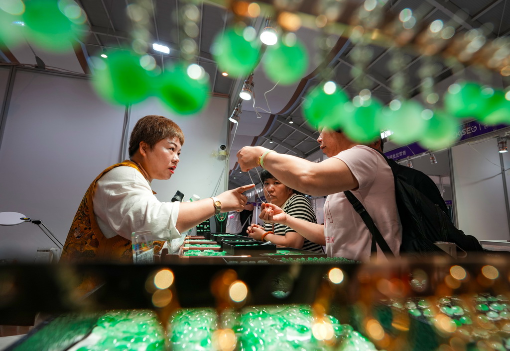 7月10日,参展商(左)在昆明石博会上向消费者介绍玉石。