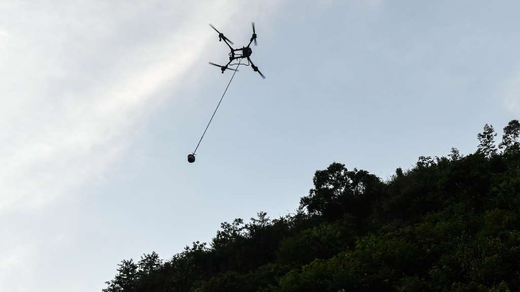 橋隧工人遙控無人機給隧道山體上的施工點運送混凝土（7月15日攝）。