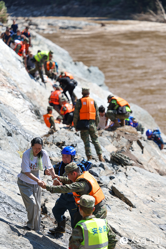 7月29日,北京市怀柔区琉璃庙镇双文铺村附近,解放军陆军某部官兵和蓝天救援队队员协助受困游客和村民们转移。