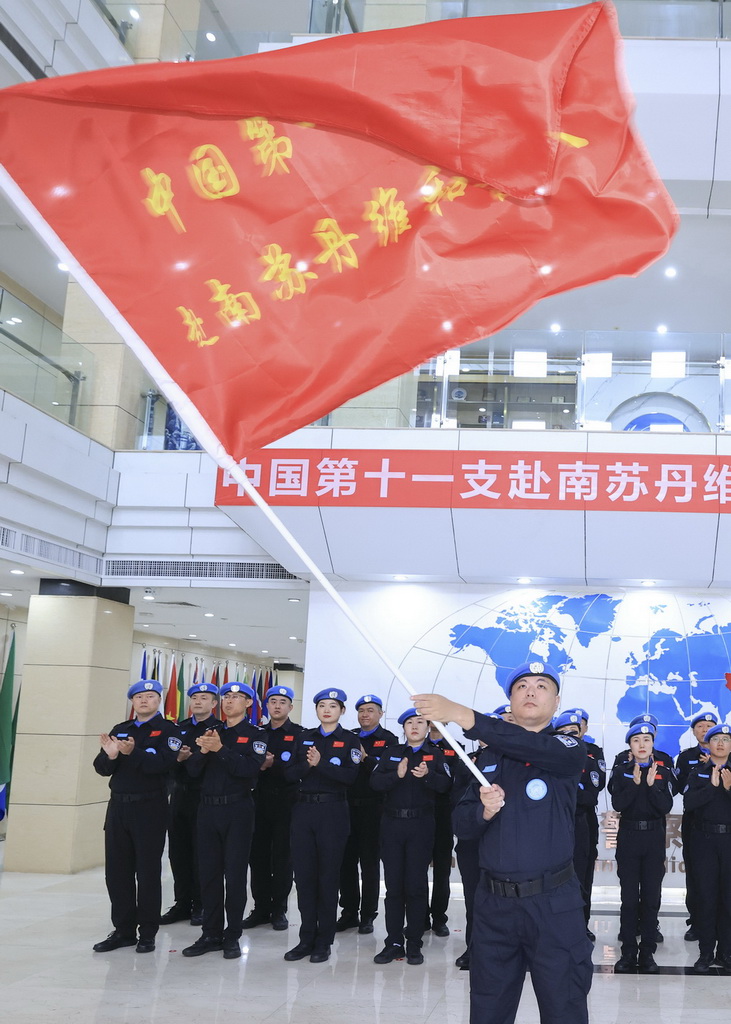 8月5日,中国第十一支赴联合国南苏丹任务区维和警队队长李冬(前)在出征仪式上展示队旗。