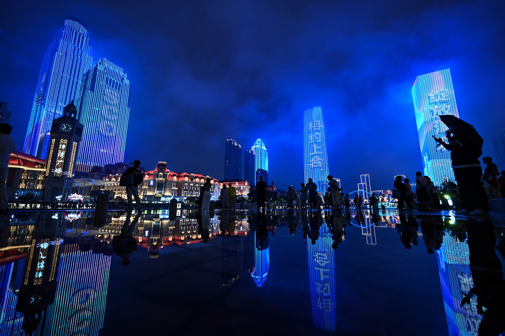 市民游客在雨中欣赏天津海河岸边的夜景（8月24日摄）。新华社记者 赵子硕 摄