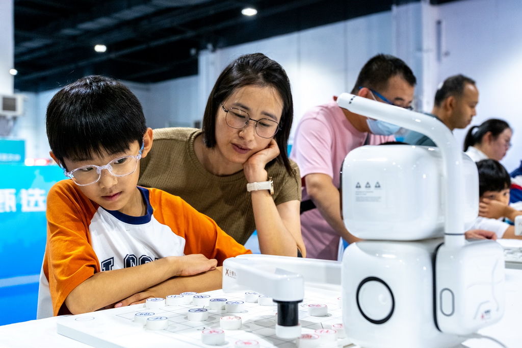 8月31日,在内蒙古呼和浩特市2025北疆书展,小朋友与AI下棋机器人对弈。