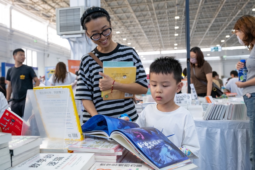 8月31日,小朋友在内蒙古呼和浩特市2025北疆书展阅读书籍。