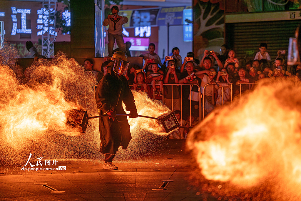 10月1日，在四川省眉山市仁寿县怀仁街道栖西里商业街广场，民间艺人正在表演“火壶”技艺，引得不少市民和游客驻足观看。潘帅摄（人民图片网）