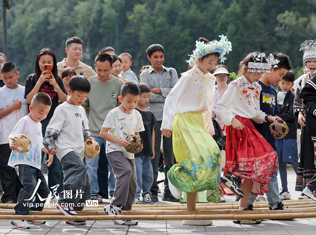 10月1日，小朋友在贵州省遵义市乌江寨景区参加“手忙脚乱”体验项目。袁福洪摄（人民图片网）