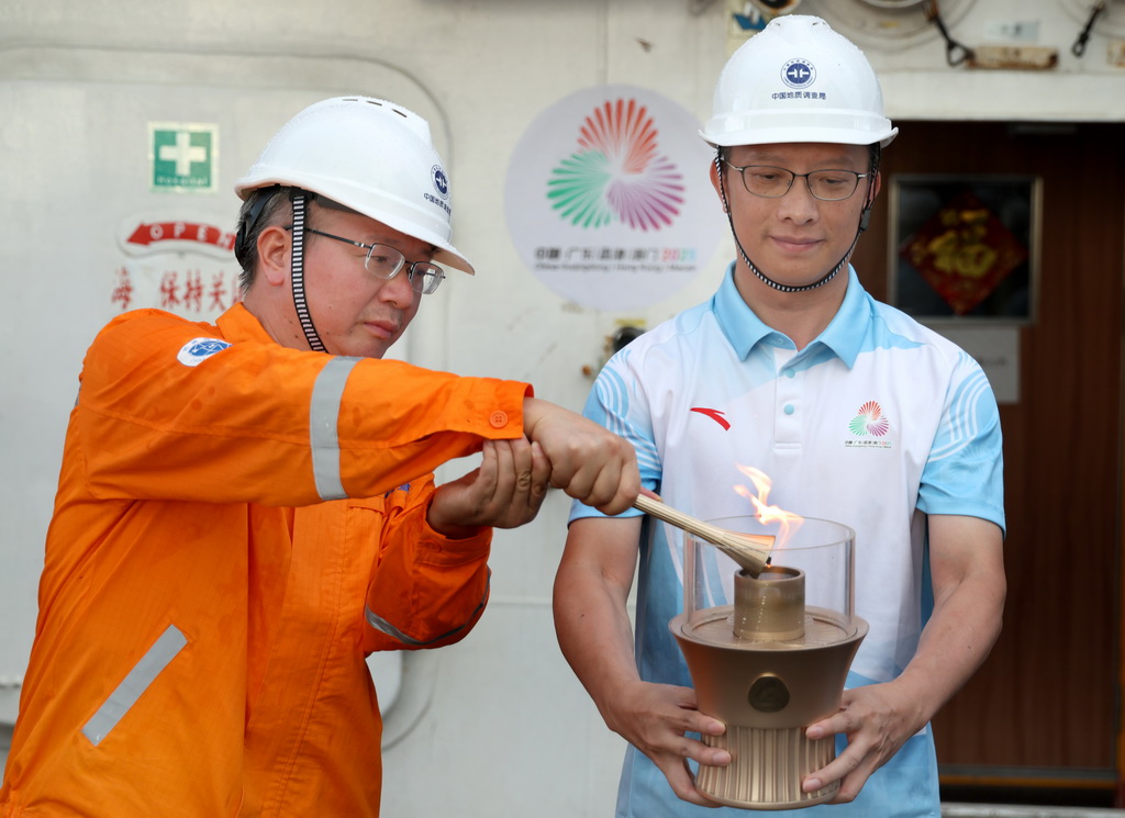 在科考船甲板面，“源火”采集组副组长，广州海洋地质调查局副总工程师沙志彬（左）用引火棒将“源火”转移至“源火”盒（9月18日摄）。