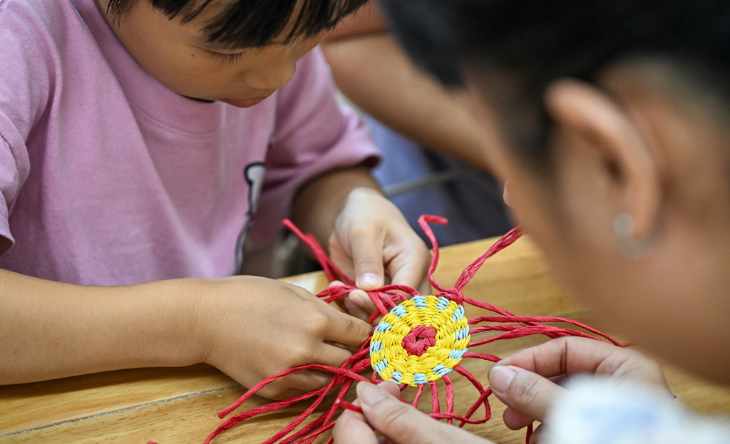 10月12日,在海南省文化馆,小朋友学习东山草编技艺。