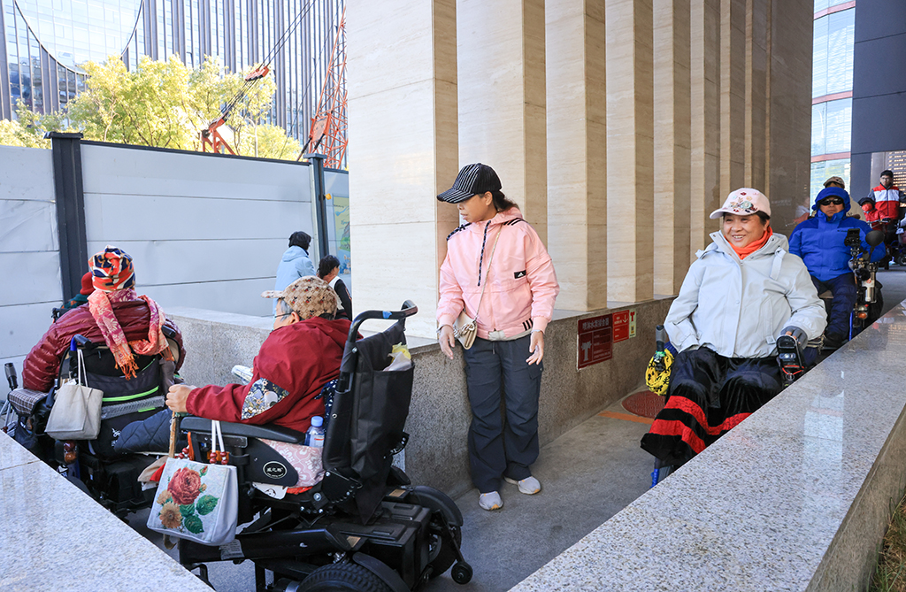 10月26日，志愿者在帮助肢体残疾人士观影后离开。