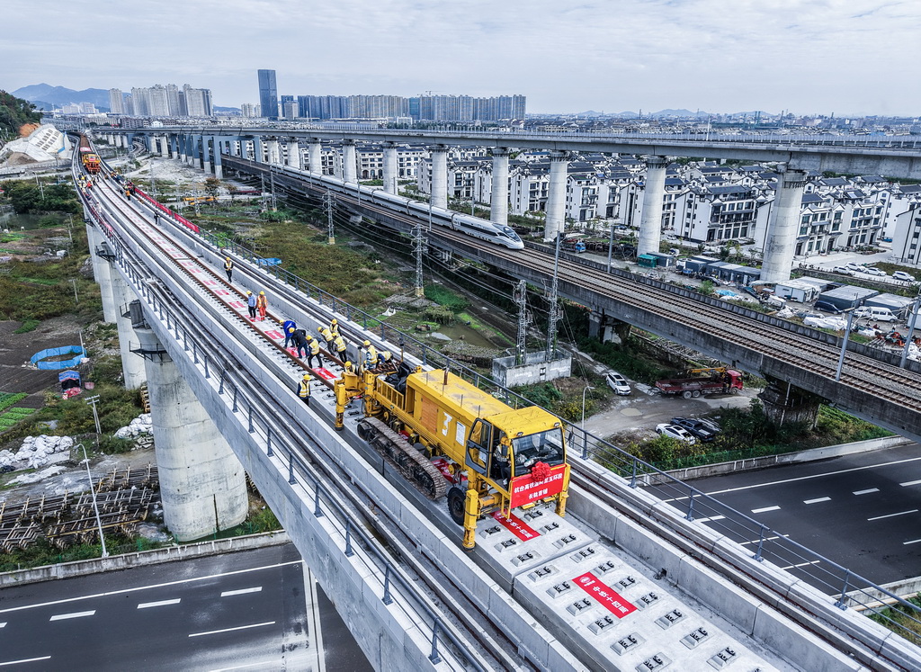 11月5日,在浙江省台州市杭台高铁温岭至玉环段施工作业现场,中铁十四局工作人员操作长轨牵引车进行铺轨作业(无人机照片)。