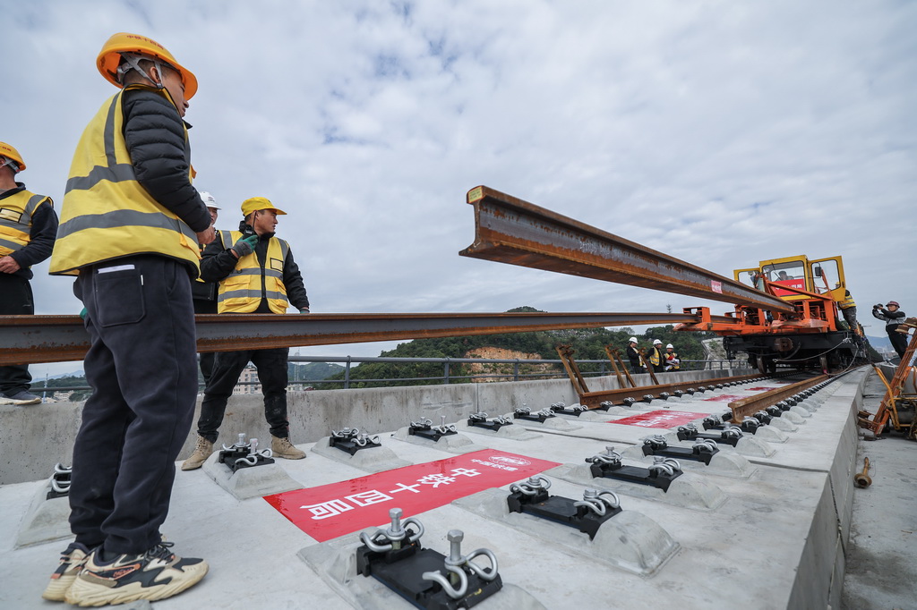 11月5日，在浙江省台州市杭台高铁温岭至玉环段施工作业现场，中铁十四局工作人员协助长轨牵引车进行铺轨作业。