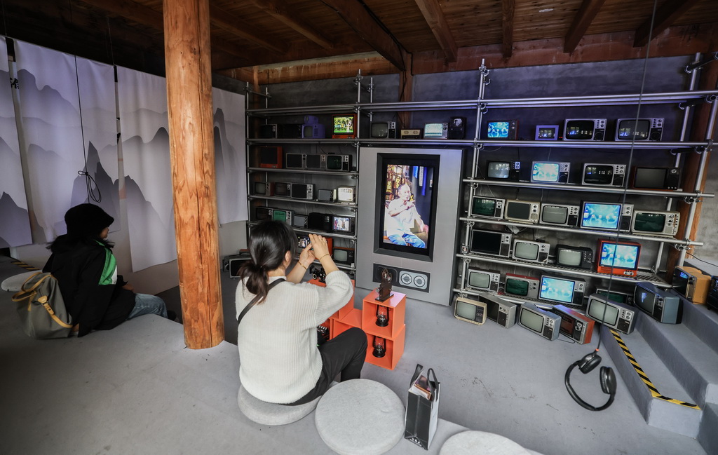 11月5日，游客在濮院时尚古镇的互联网生活嘉年华观看老旧电视机播放的濮院传统生活场景。