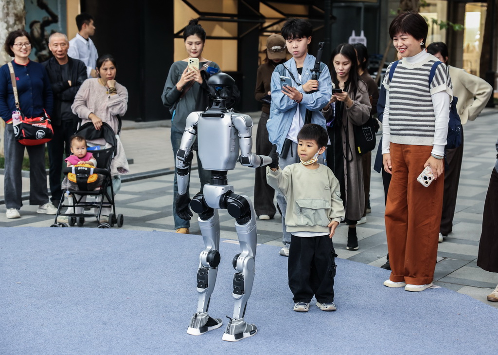 11月5日，游客在濮院时尚古镇与人形机器人互动。