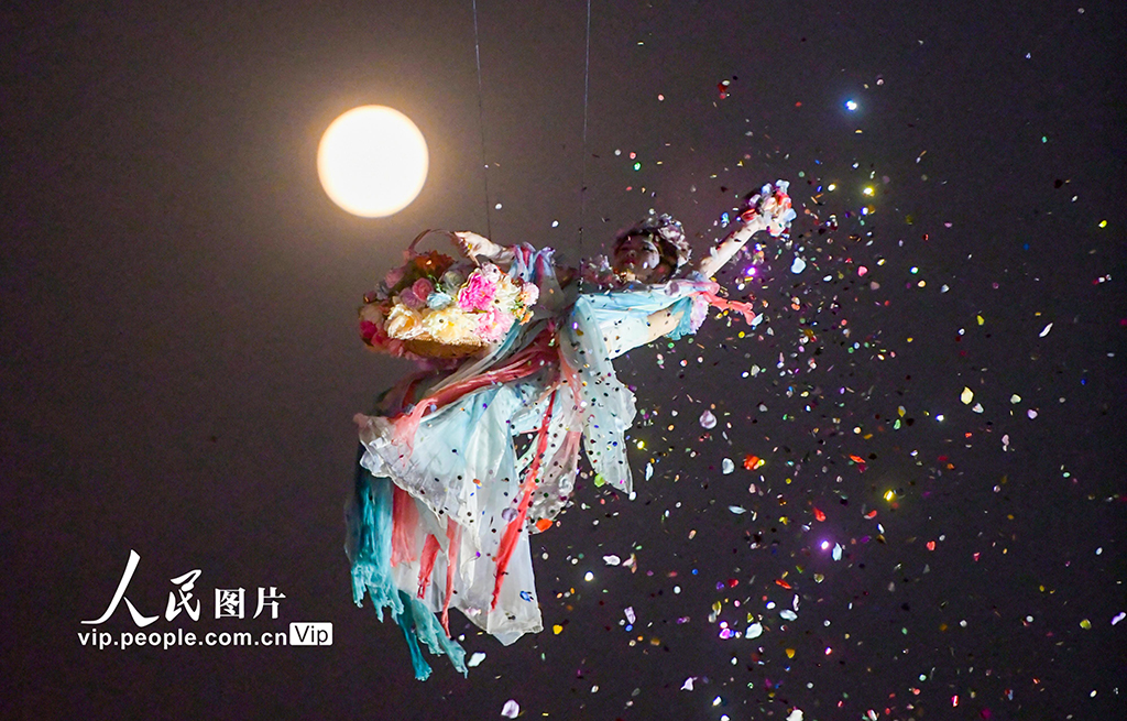 2025年11月5日，在河南省洛阳市洛邑古城景区，演员表演的“仙女散花”与“超级月亮”构成一幅美丽的画卷。张怡熙摄（人民图片网）