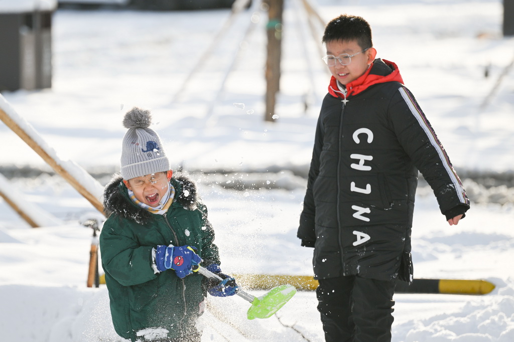 11月6日，两名男孩在乌鲁木齐市水磨沟区的一处公园里玩雪。新华社记者 辛悦卫 摄
