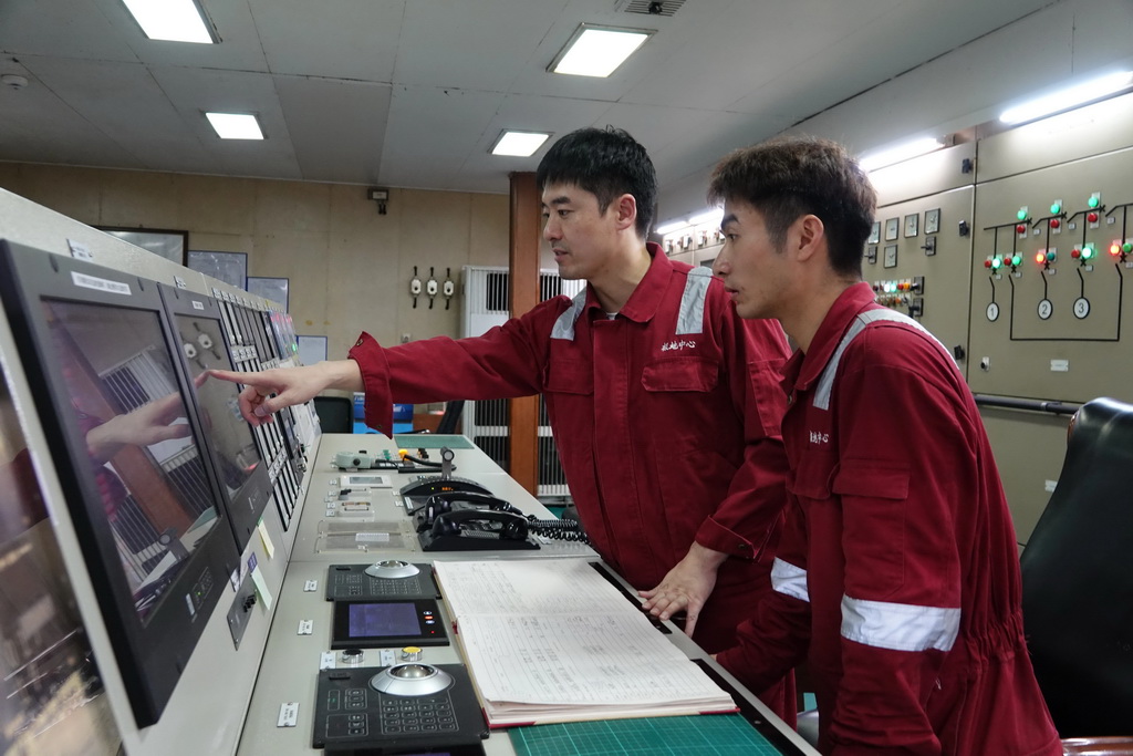 北京时间11月8日,大管轮董恒(左)在集控室内为机工田健伟讲解主要设备报警信息。新华社记者 顾天成 摄