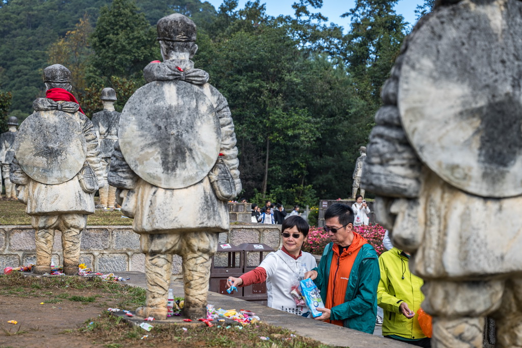 11月20日，游客在雲南省保山市龍陵縣鬆山戰役舊址參觀時向娃娃兵雕像敬獻糖果。
