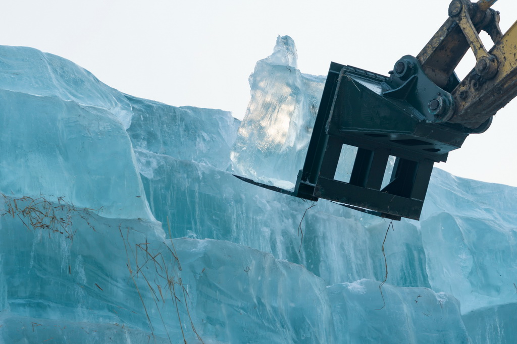 11月24日，在哈尔滨冰雪大世界存冰场，工程车辆从冰垛上取冰。