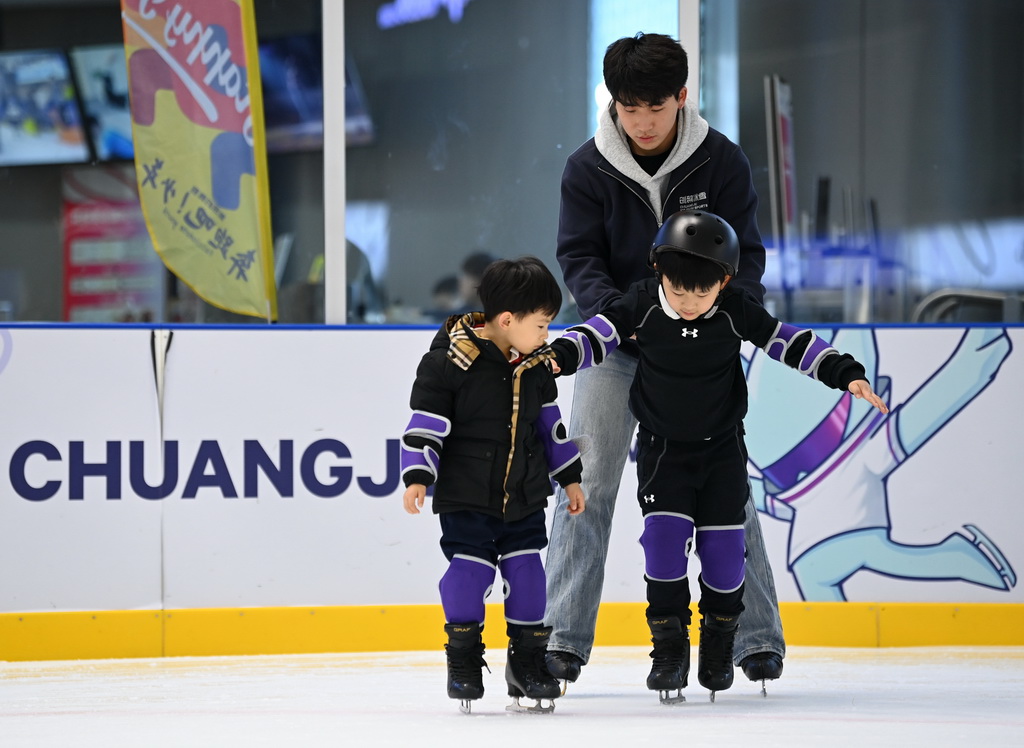 12月3日，教练马帅（中）在冰上运动公益课上指导初学滑冰的小学员。