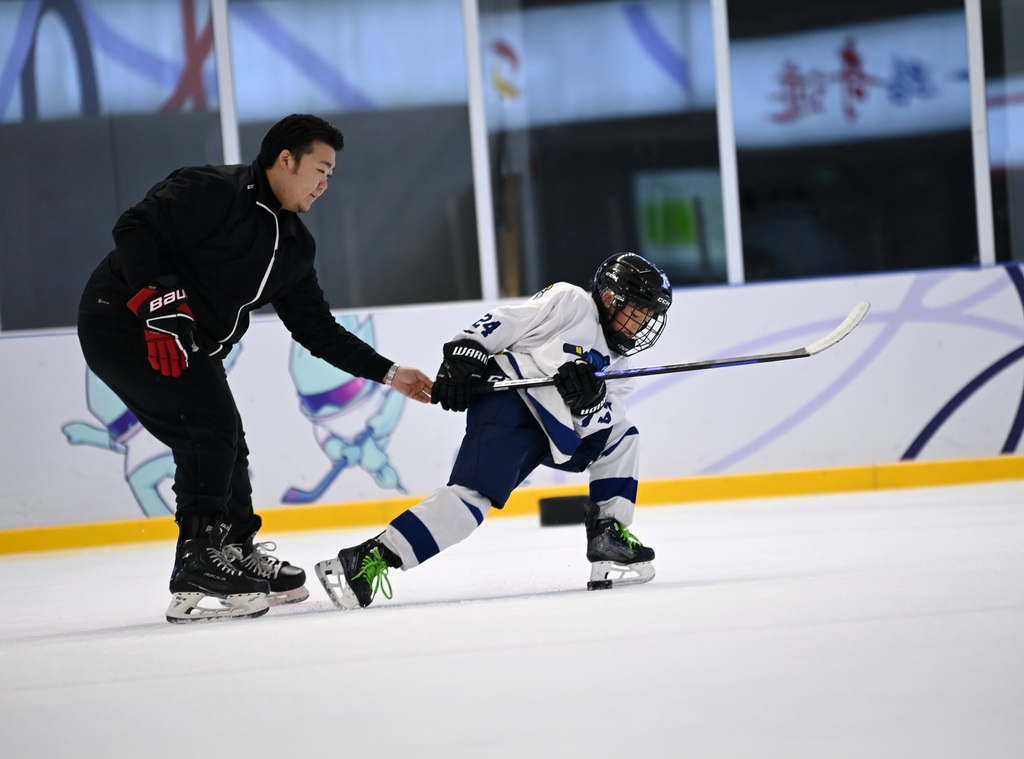 12月3日，冰球教练王恺英（左）在冰上运动公益课上指导小学员。