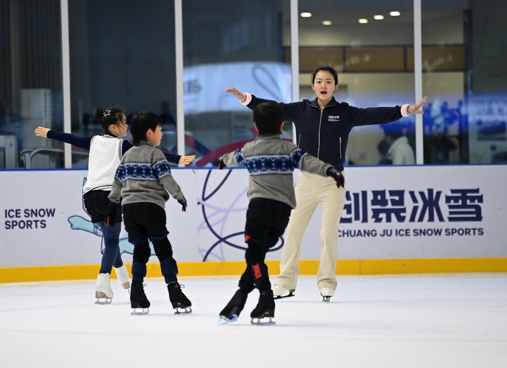 12月3日,花样滑冰教练胡雨晴(右)在冰上运动公益课上指导小学员。