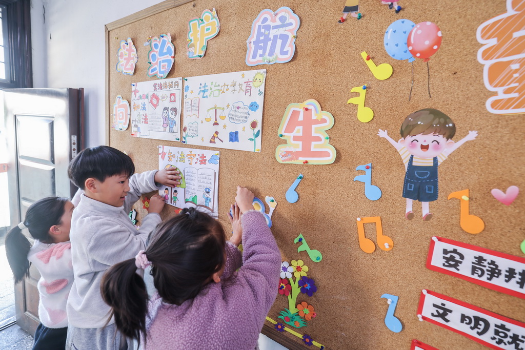 12月9日,诸暨市暨南街道中心学校王家井小学的学生把自己创作的法治宣传画贴到教室的宣传栏中。