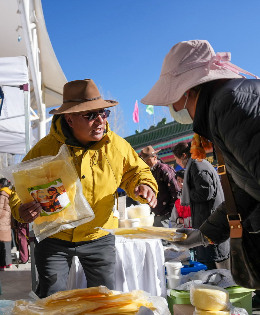 12月10日，商户在拉萨市宗角禄康公园的供销大集上向顾客介绍商品。