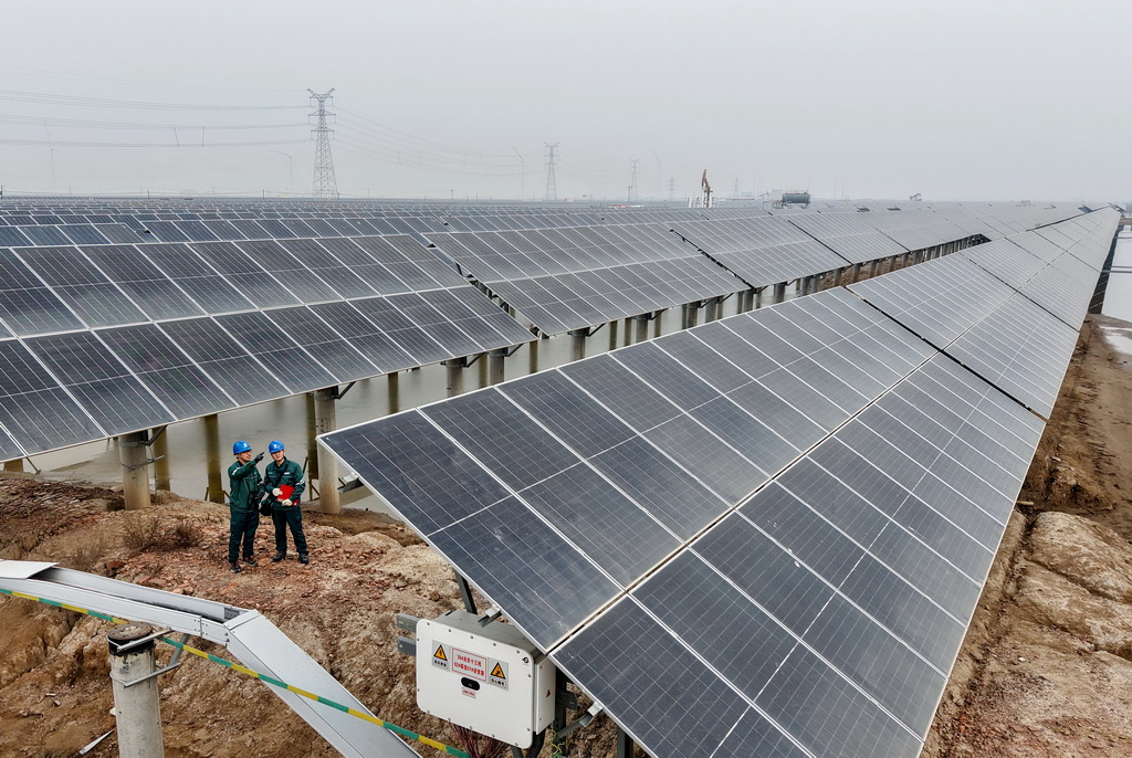 12月10日，國網滄州供電公司的工人在轄區渤海新區黃驊市一處“漁光互補”光伏發電場巡檢（無人機照片）。