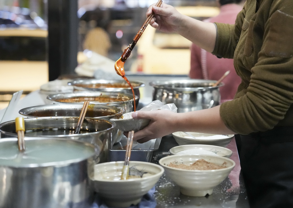 12月12日，在四川省广元市一家凉面馆，工作人员在调配凉面调料。新华社记者 连振 摄