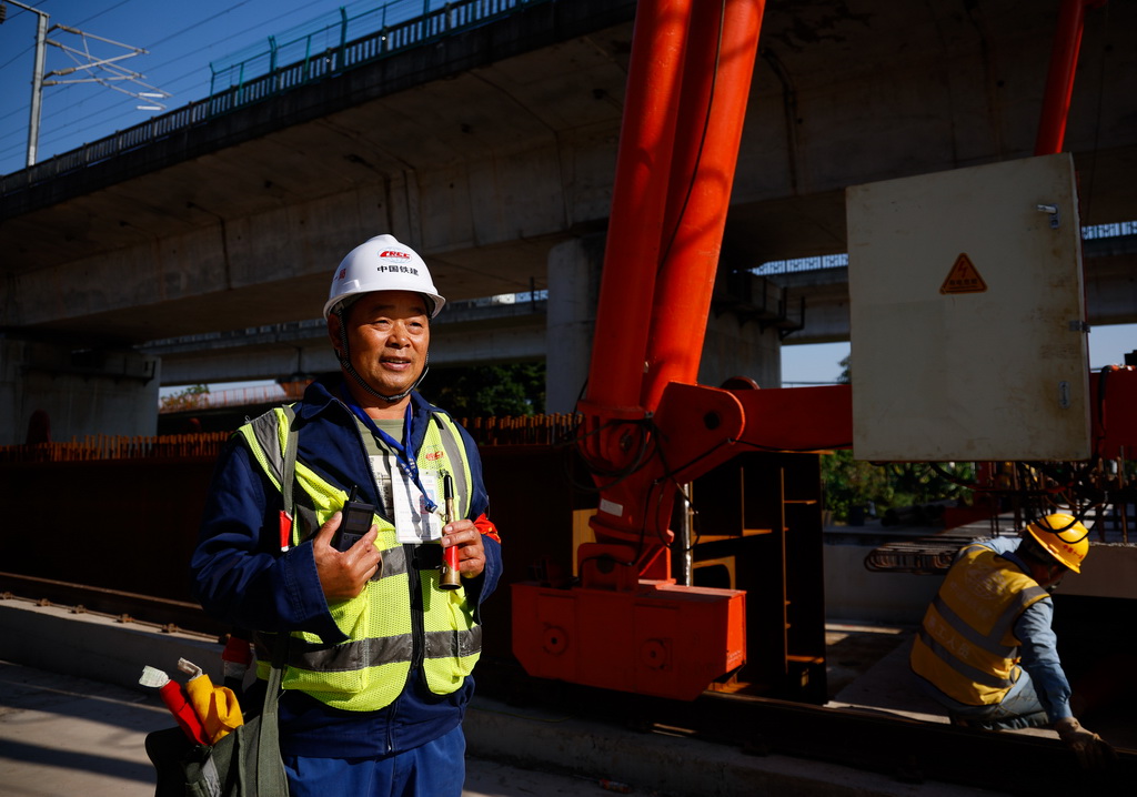 12月21日，安全防护员罗强手持防护铜笛和通讯设备在广南联络线广州南左右线大桥施工现场巡检。