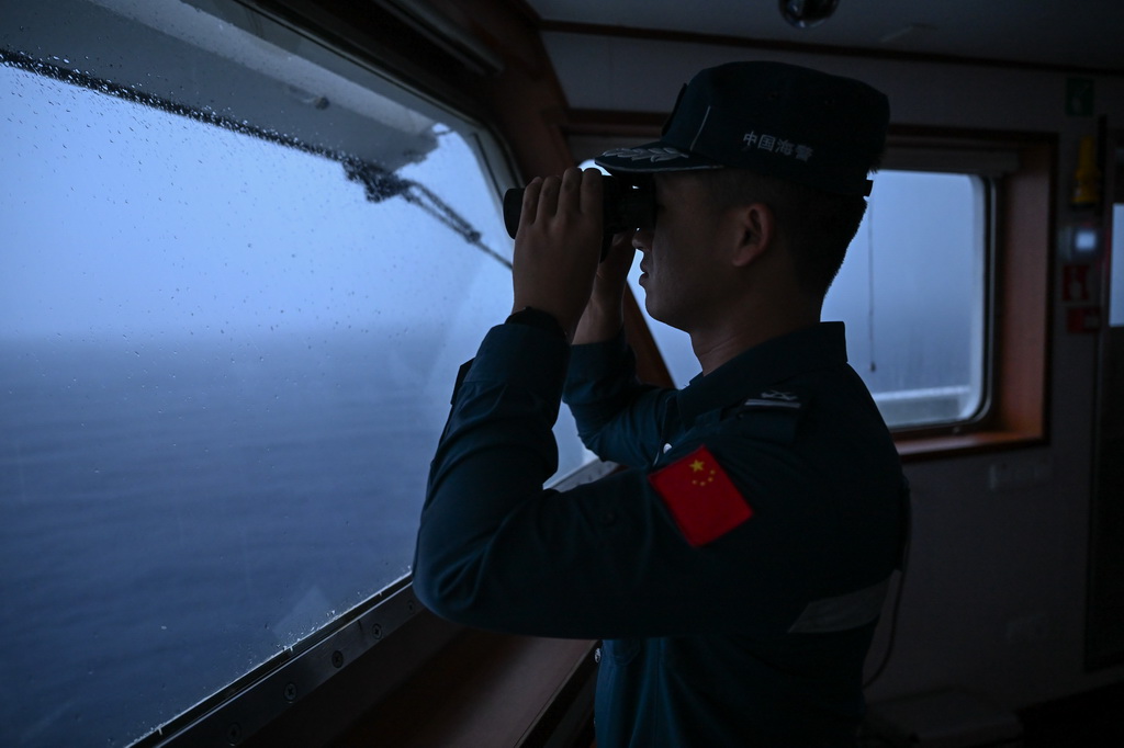 11月22日日出前,在巡航值守于中国南海黄岩岛海域的黄岩舰上,海警执法员在驾驶室查看周边海域情况。