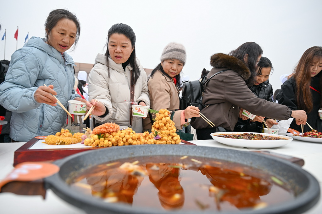 12月30日,当地市民在比赛现场品尝特色美食。