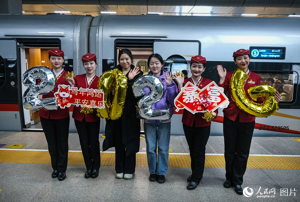 12月30日，C2026次列車乘務人員與旅客在站台合影留念。