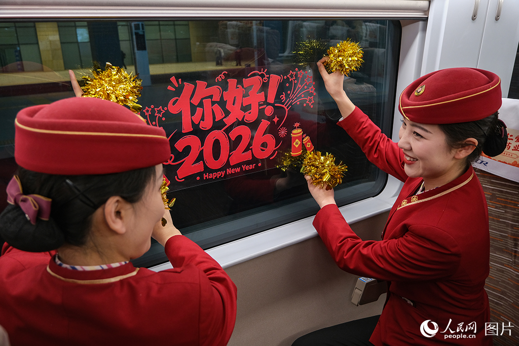 12月30日，C2026次列車上乘務人員布置車廂，粘貼迎新年窗貼。