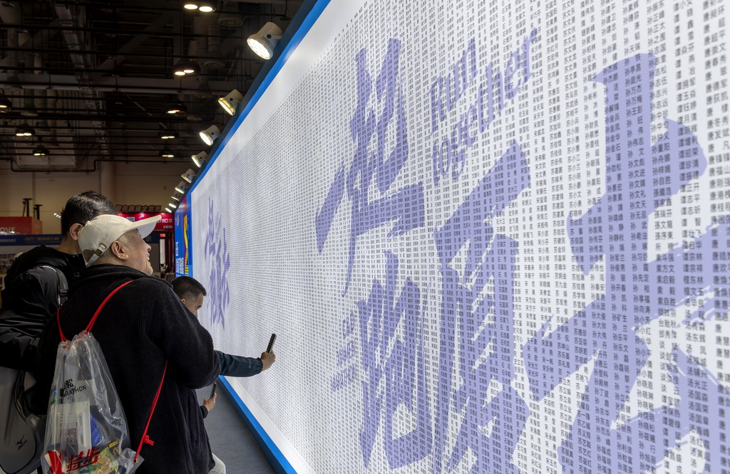 1月8日,参加厦门马拉松赛的选手在博览会厦门马拉松跑者姓名墙上寻找自己的名字。