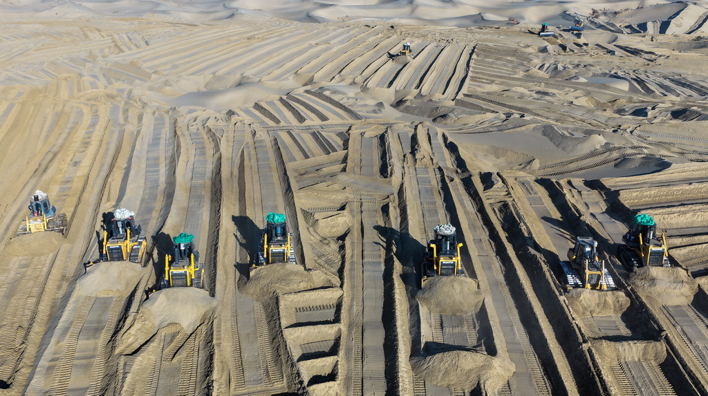 在新疆和田地区墨玉县喀瓦克乡，大型机械在沙漠中穿梭作业、平整沙地（1月11日摄，无人机照片）。