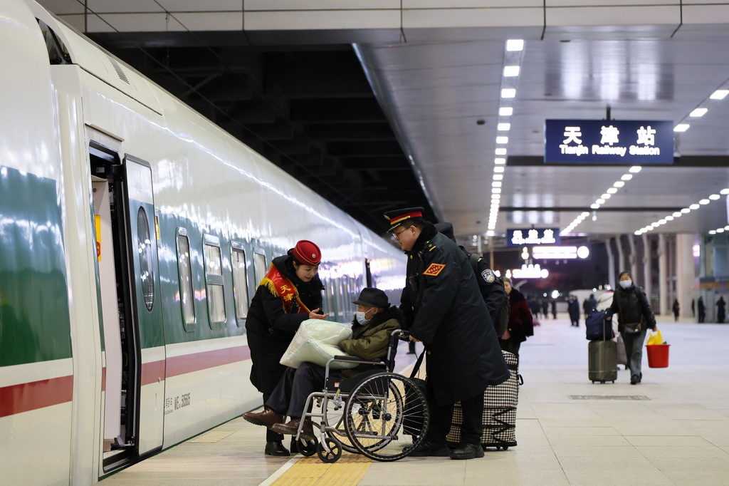 1月19日,鐵路工作人員在天津站服務重點旅客上車。