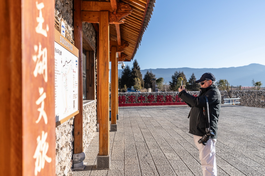 1月18日,一名游客在玉湖村游客中心前拍摄景区导览图。新华社记者 高咏薇 摄