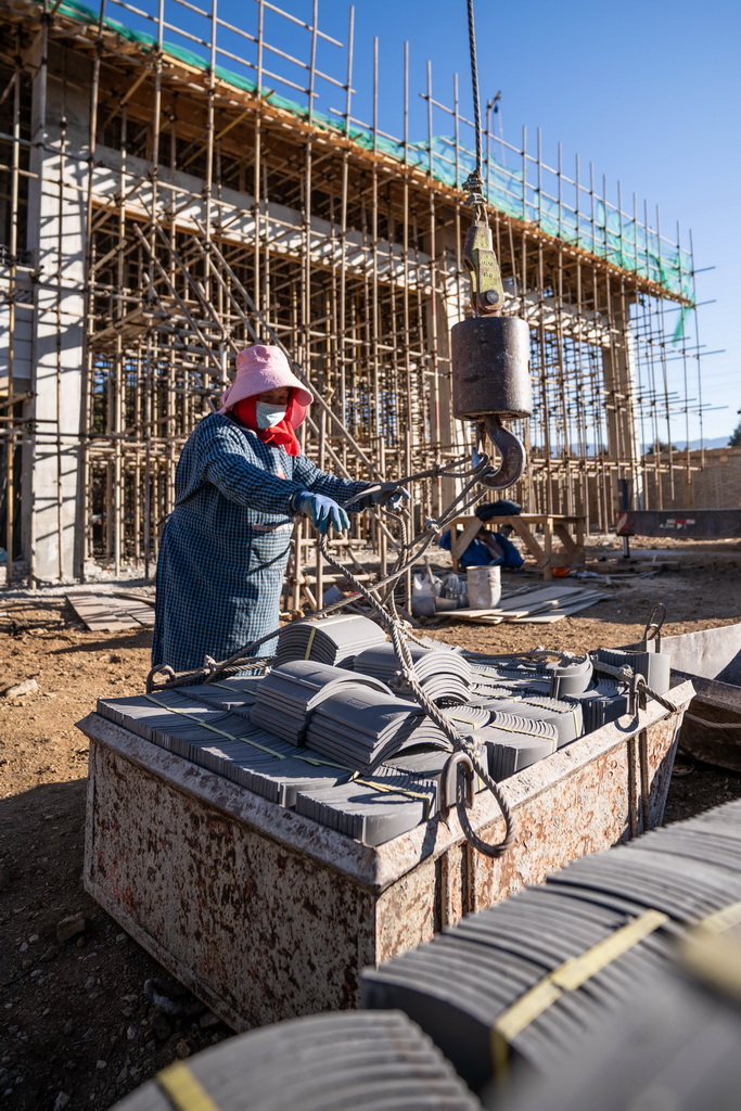1月18日,工人在玉湖村一处垃圾中转站建设工地将瓦片挂上吊车。新华社记者 高咏薇 摄
