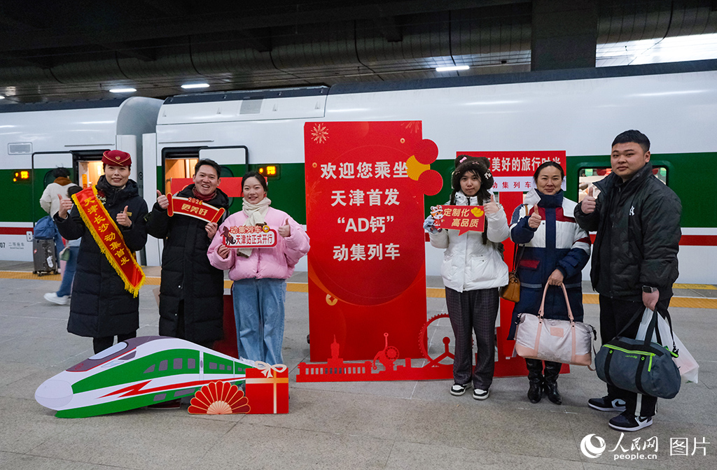 1月19日，天津首趟開出天津至長沙動力集中型動車組列車乘務人員與旅客在站台合影留念。楊寶森攝