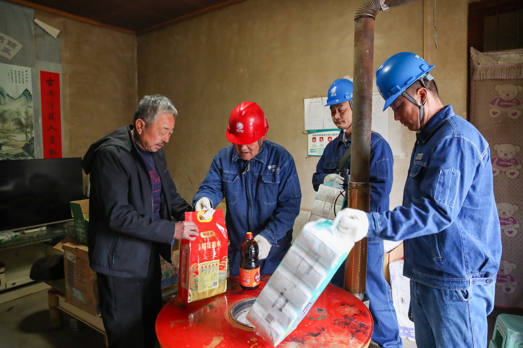 1月18日,在甘肅省隴南市兩當縣泰山鄉同心村,楊店供電所職工將代購的生活物資交給村民曹永禮。