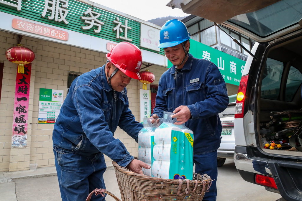 1月18日,在甘肅省隴南市兩當縣泰山鄉同心村,楊店供電所所長宋剛(左)和工友鄒小亮將代購的生活物資裝進背簍,准備上山。