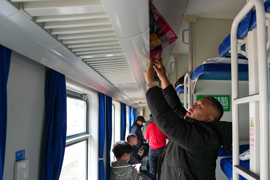 1月25日,在廣州火車站,旅客在K303次列車上擺放行李。