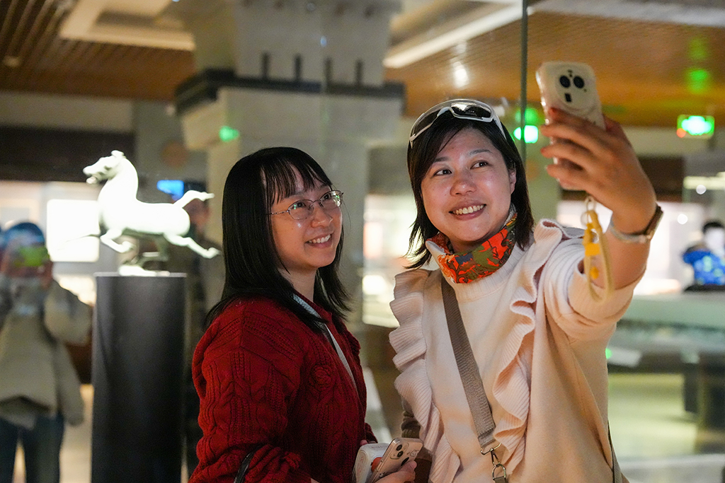 1月26日晚，在甘肅省博物館二樓絲綢之路文明展廳，觀眾與東漢銅奔馬（復制品）自拍合影。