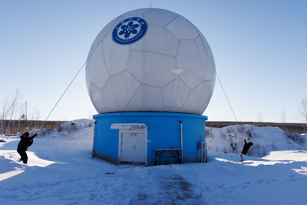 1月25日，工作人員李強（左）和田冬在一起清除天線罩頂上積雪。