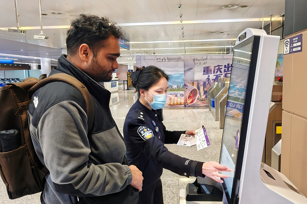 在重慶江北國際機場，重慶出入境邊防檢查總站民警幫助入境的新加坡旅客填寫入境信息（1月7日攝）。