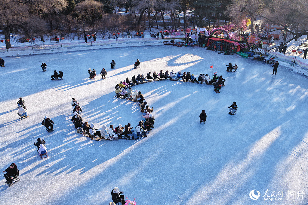 2026年1月24日，在辽宁沈阳北陵公园冰场，冰雪运动爱好者驾驶冰车组成真人版的冰上“贪吃蛇大队”，体验着与陌生人一同玩耍的趣味，在滑行中感受北方孩童冬日的快乐。人民网记者 周颂雪摄